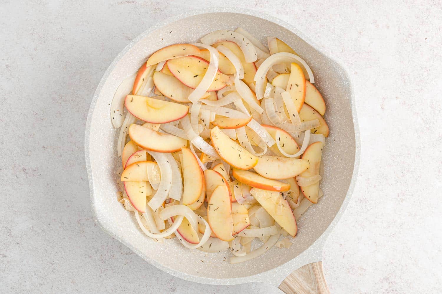 Apples and onions in a frying pan.