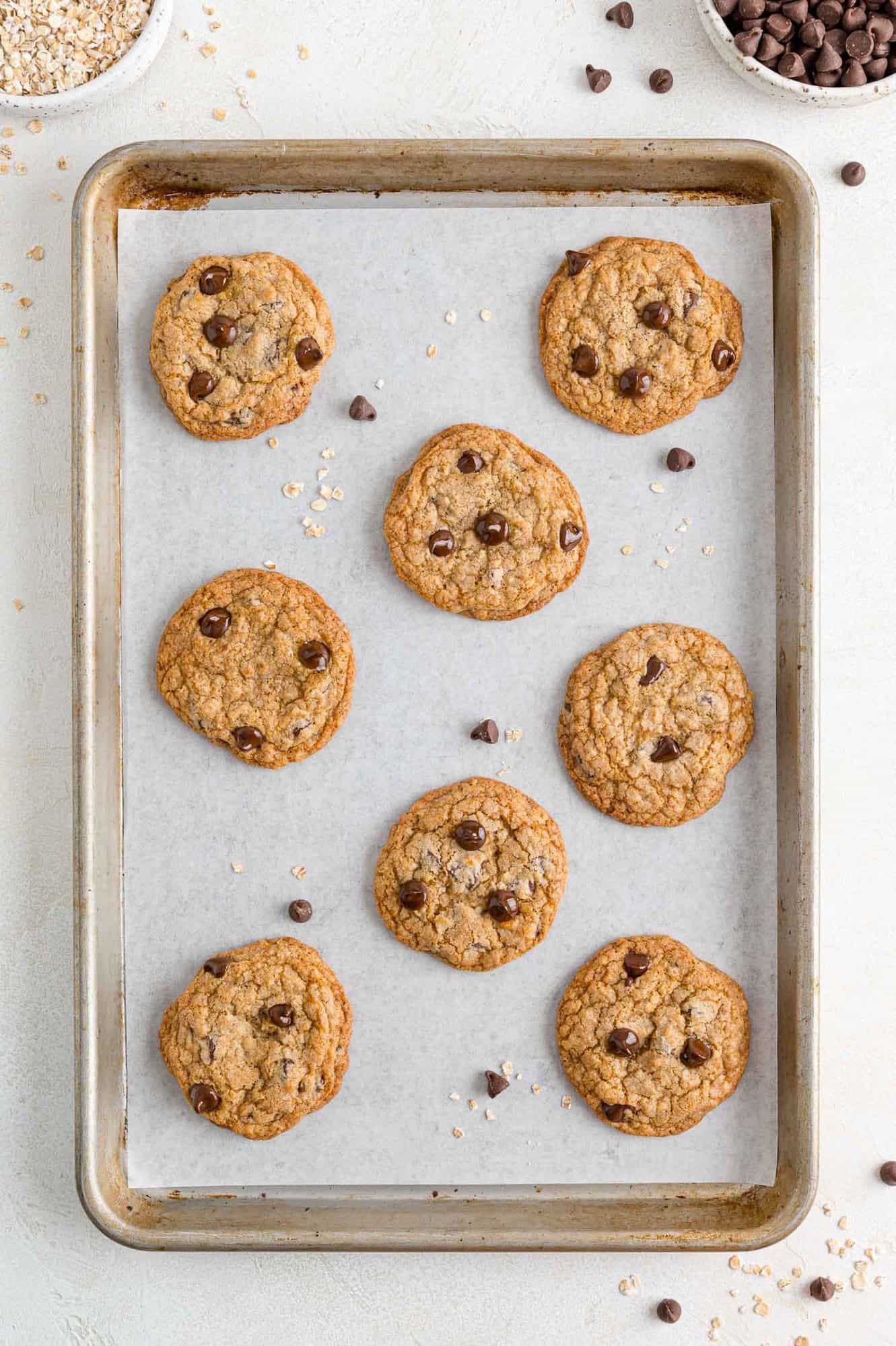 Baked cookies on sheet pan with chocolate chips sprinkled around.