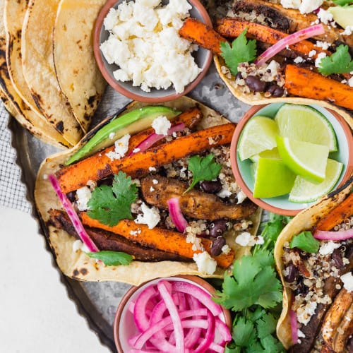 Carrot and mushroom tacos on a tray with toppings.
