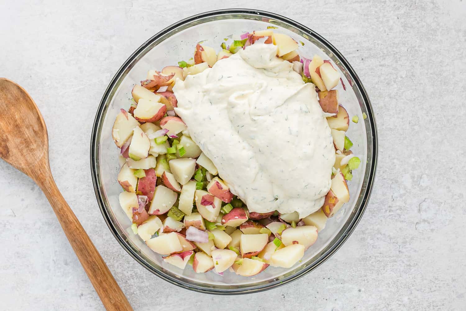 Dressing on top of potato salad ingredients, not yet mixed.