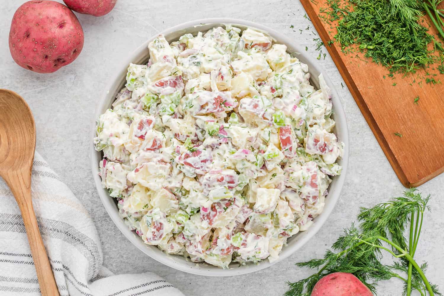 Dill pickle potato salad in a white serving bowl.