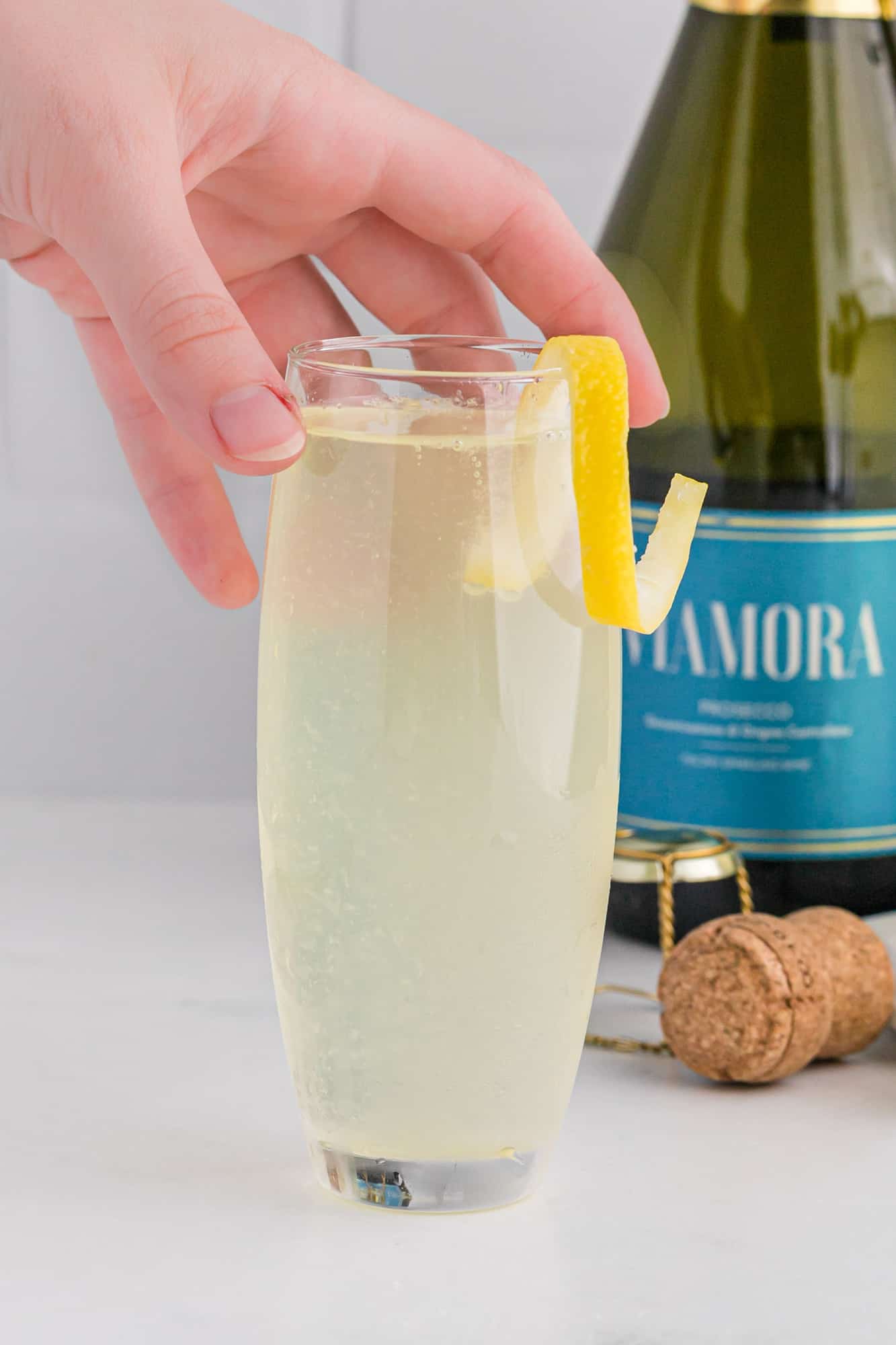 Hand holding a lemon champagne cocktail.