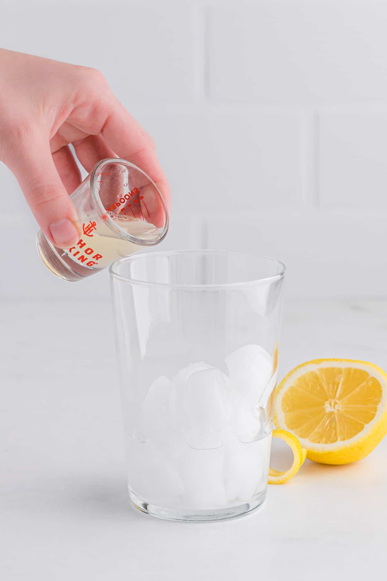 Lemon juice being poured into cocktail shaker.