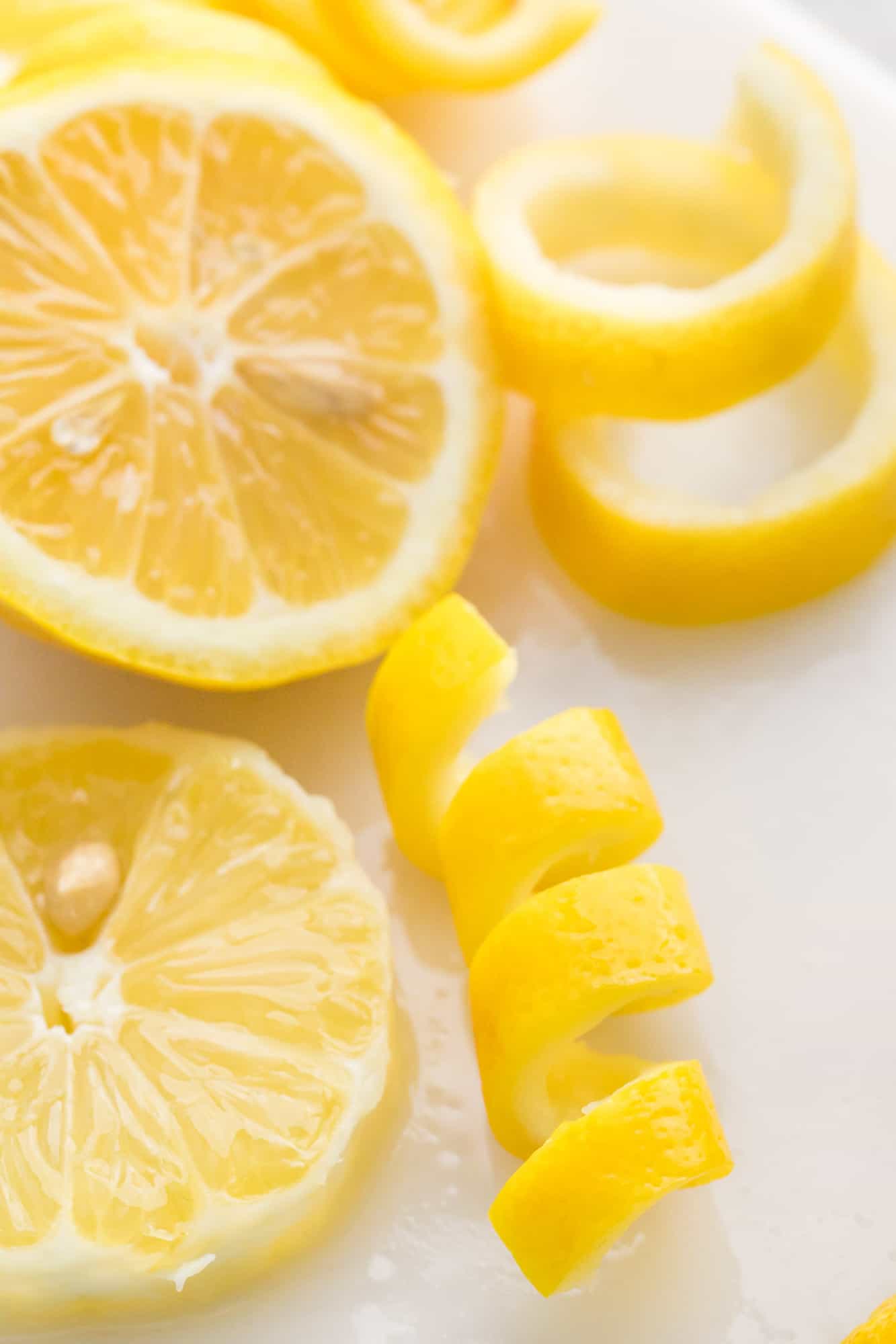 Lemon peel spiral next to lemon rounds.