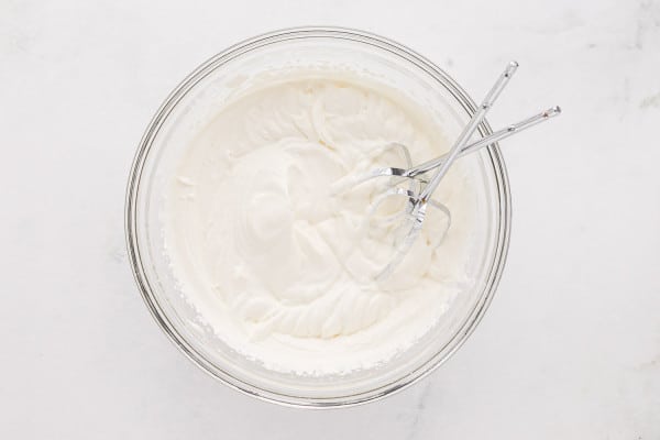 Whipped cream in a glass mixing bowl.