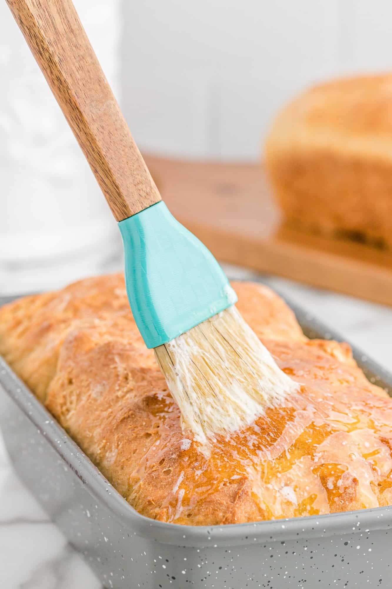 Baked bread being brushed with melted butter.