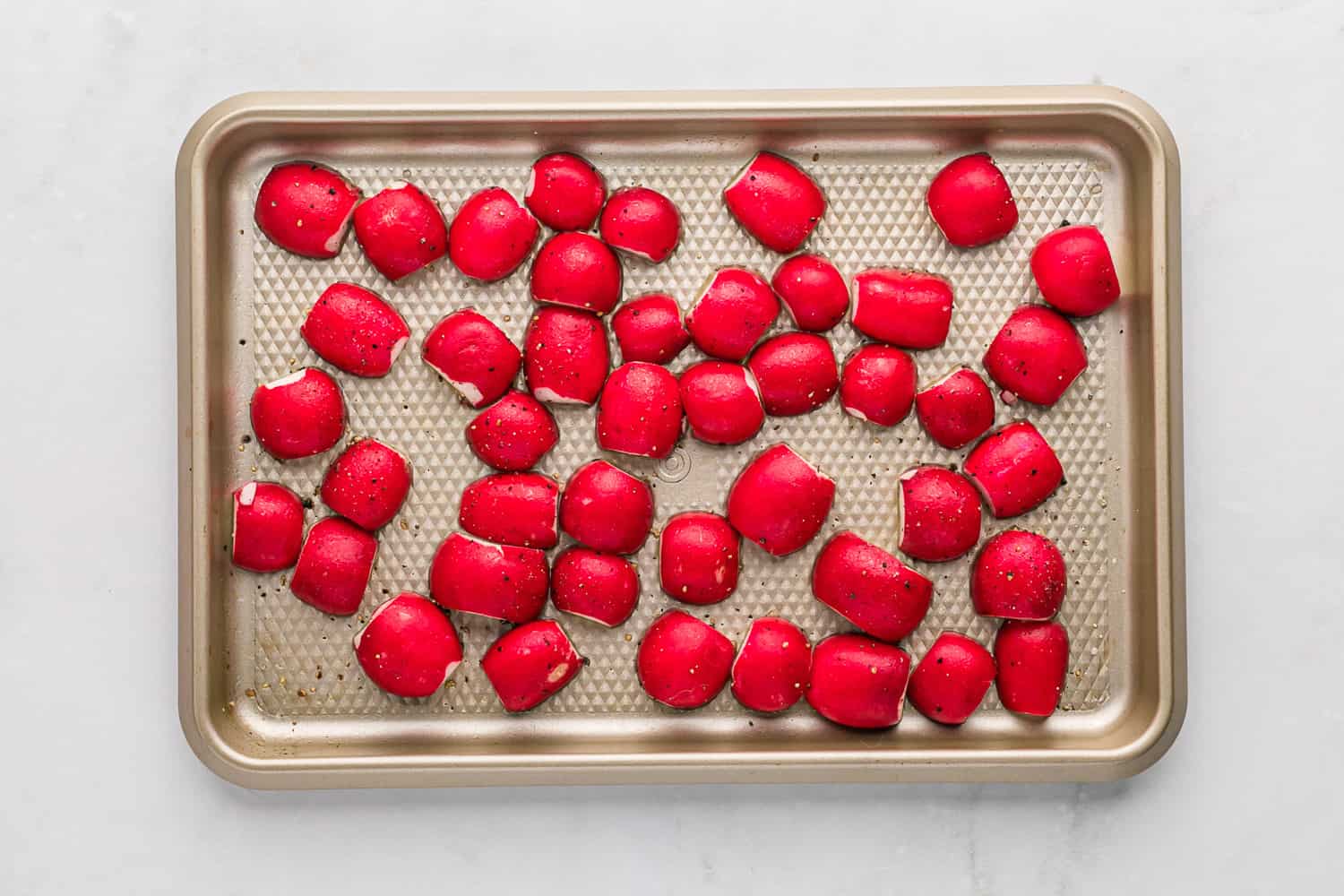 Radishes, cut side down on a sheet pan.