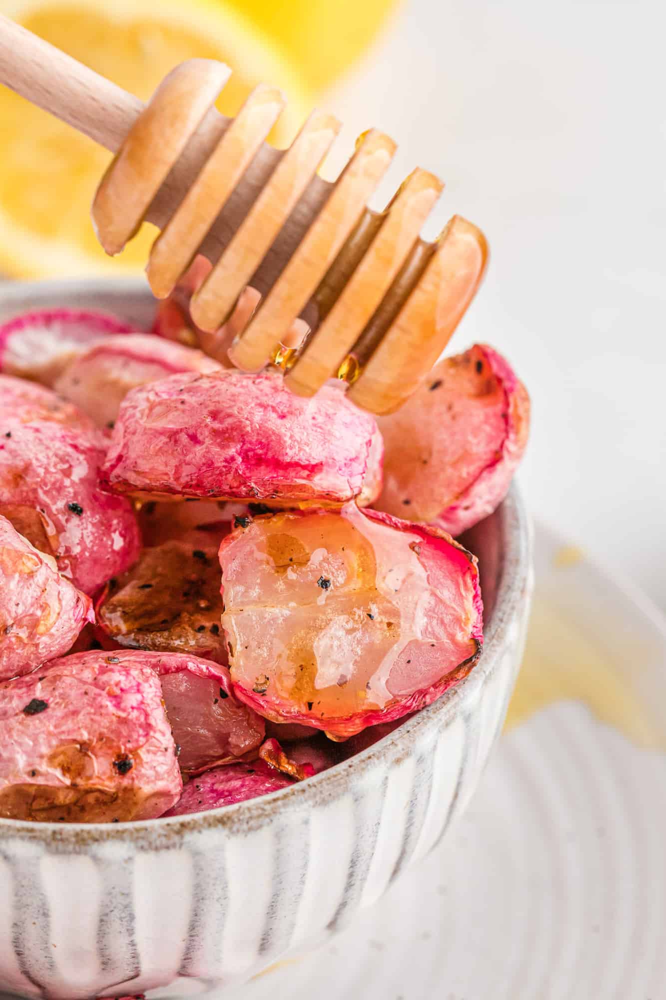 Learn how to make roasted radishes (it's easy!) and you'll come back to them constantly as a new go-to side dish that everyone will love. Even those who don't love radishes! Roasted radishes being drizzled with honey.