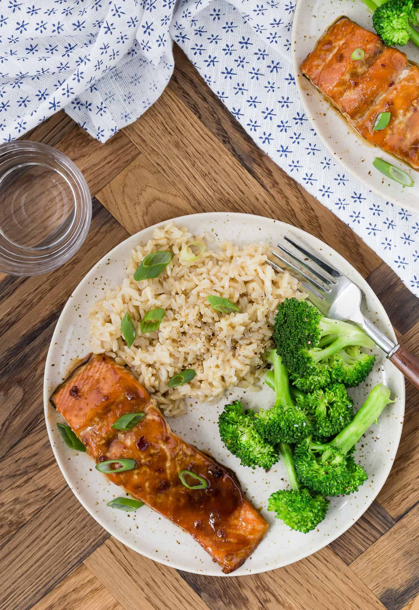 Soy and honey glazed salmon served on a plate with steamed broccoli and brown rice.