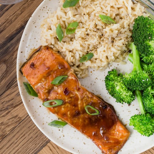 Soy glazed salmon on a plate with broccoli and rice.