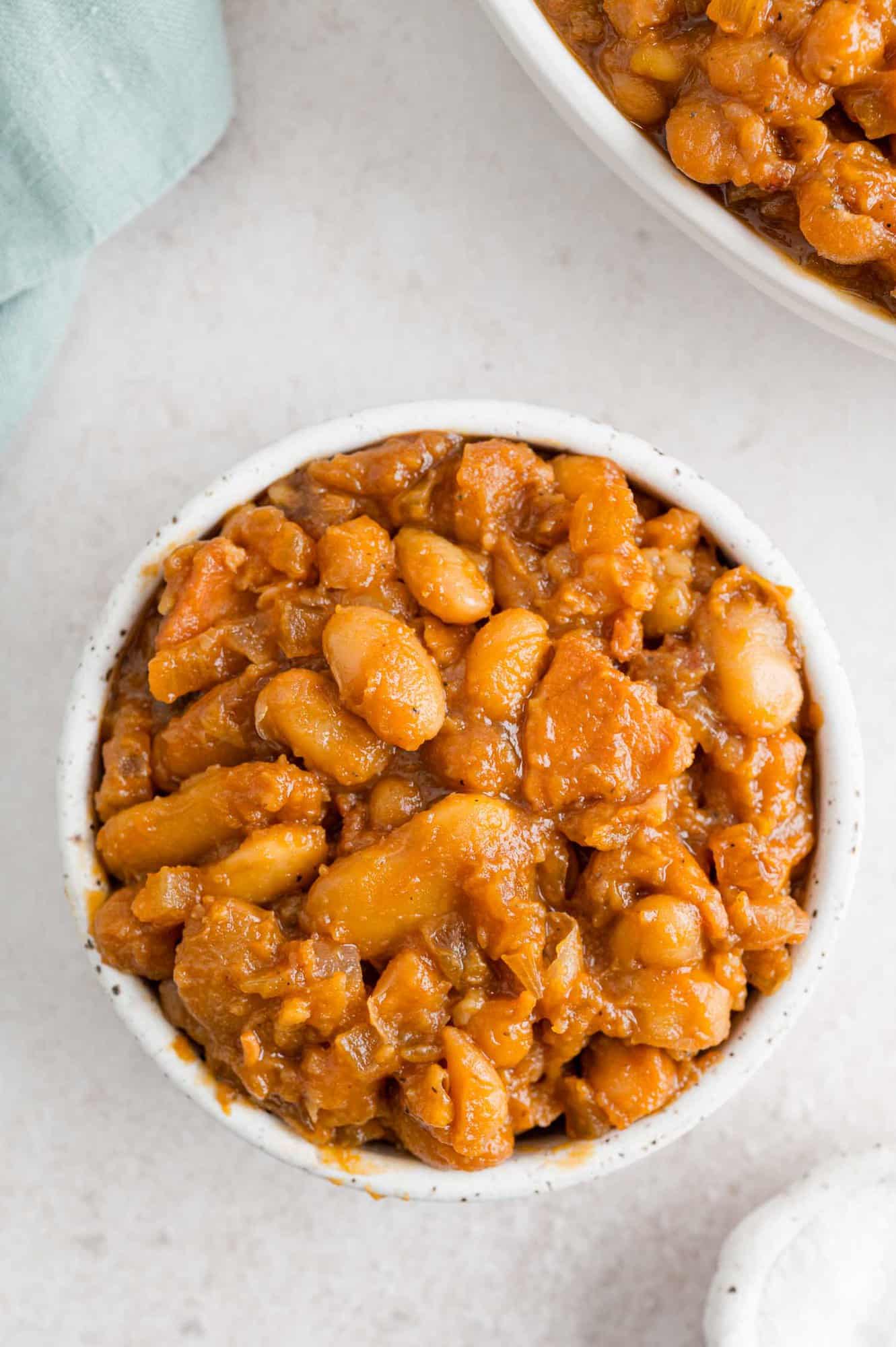 Crock pot baked beans in a small white bowl.