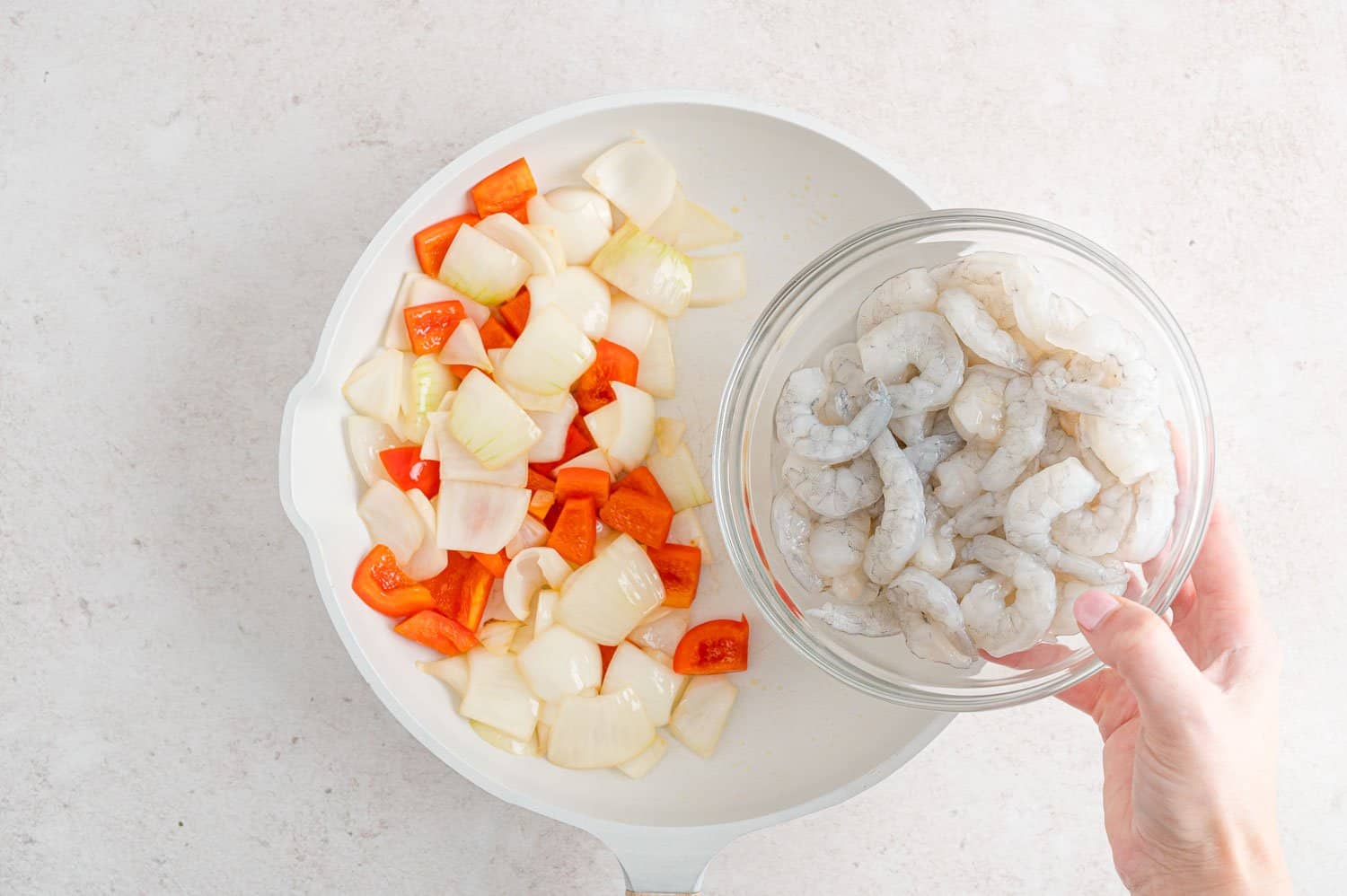 Shrimp being added to frying pan.