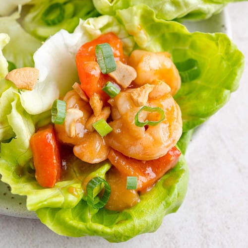Sweet and sour shrimp lettuce wrap garnished with green onion.