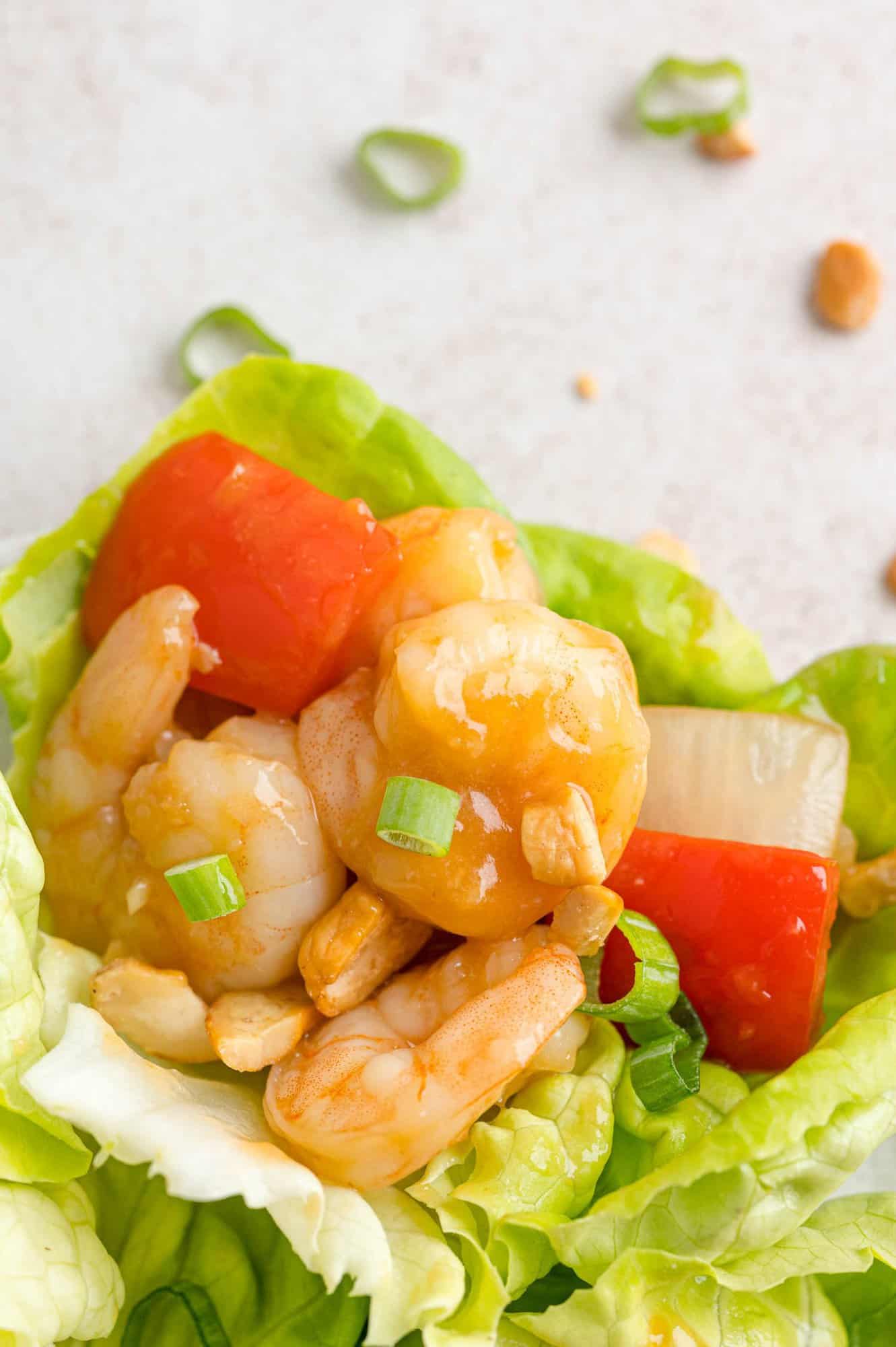 Sweet and sour shrimp lettuce wrap topped with cashews and green onions.