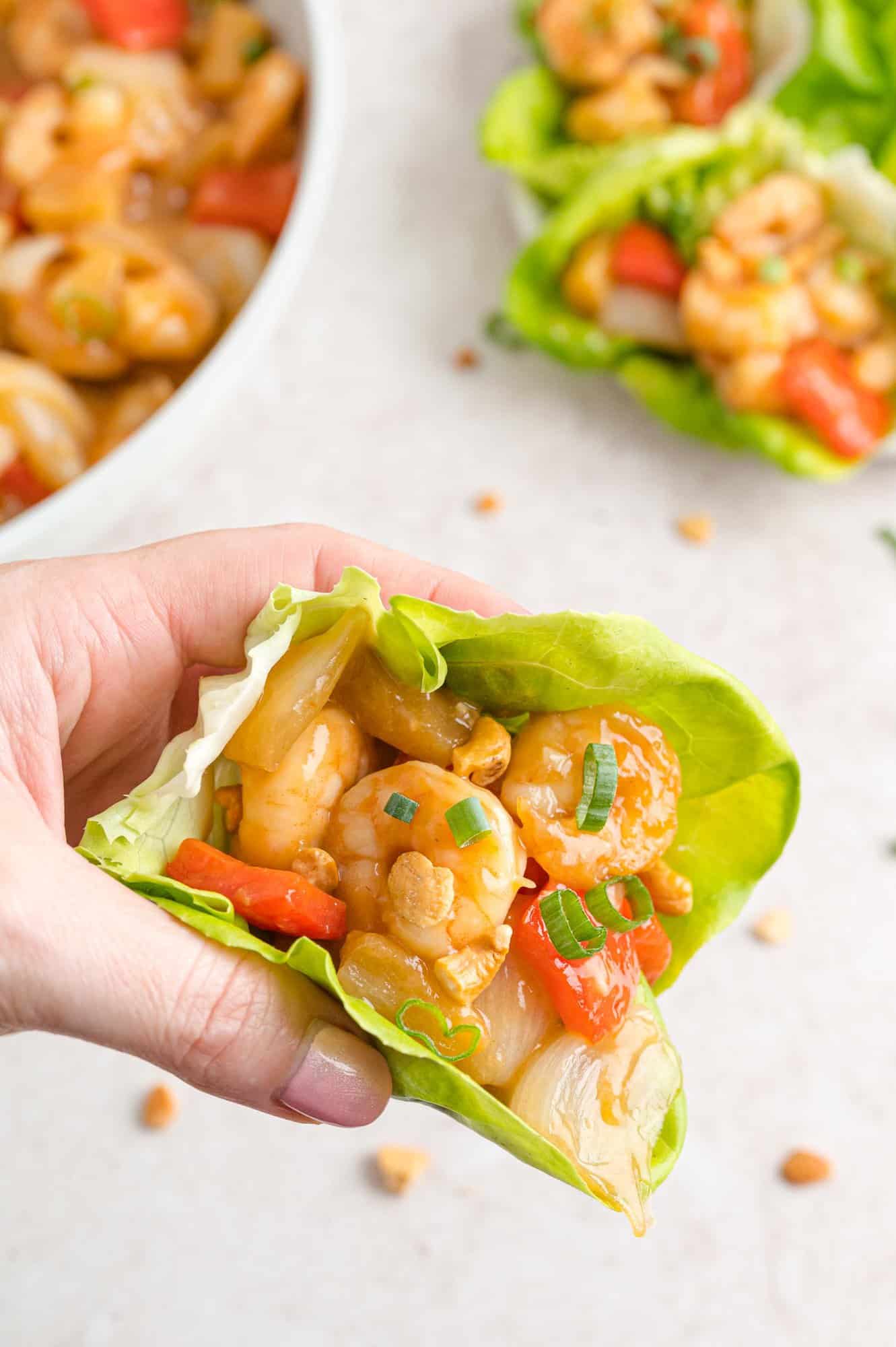 Shrimp lettuce wrap held in a hand.