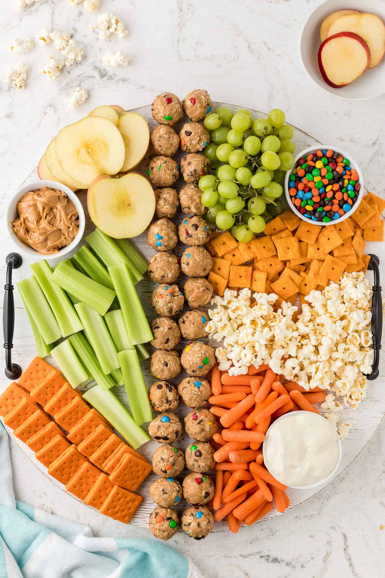 Snack board with carrots, celery, crackers, popcorn.