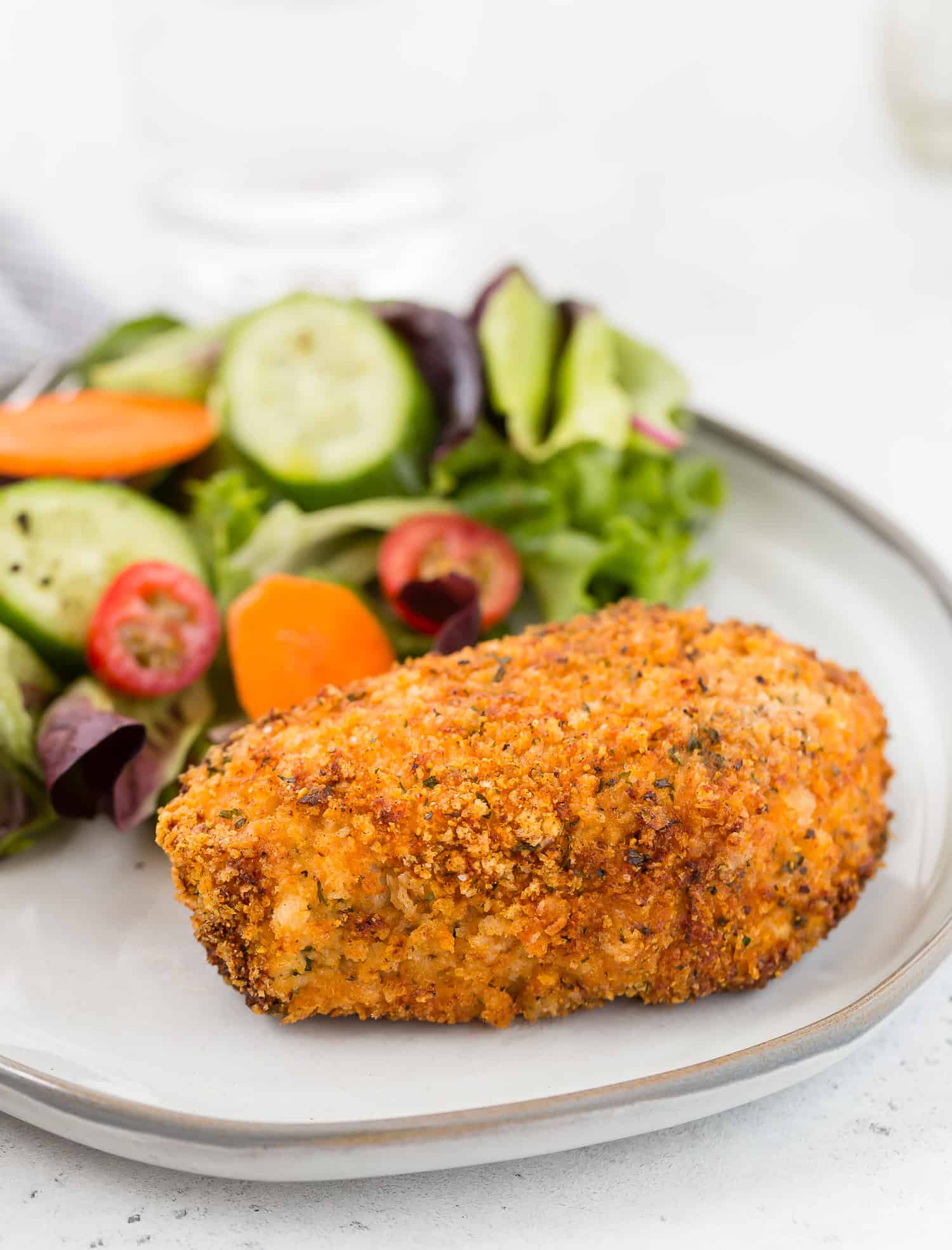 Air fryer breaded pork chop on a plate with a salad.