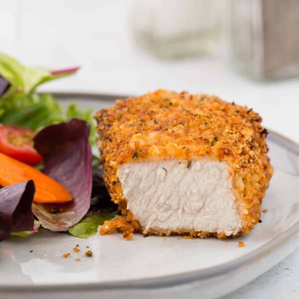 Air fryer breaded pork chop on a plate, cut to show meat.