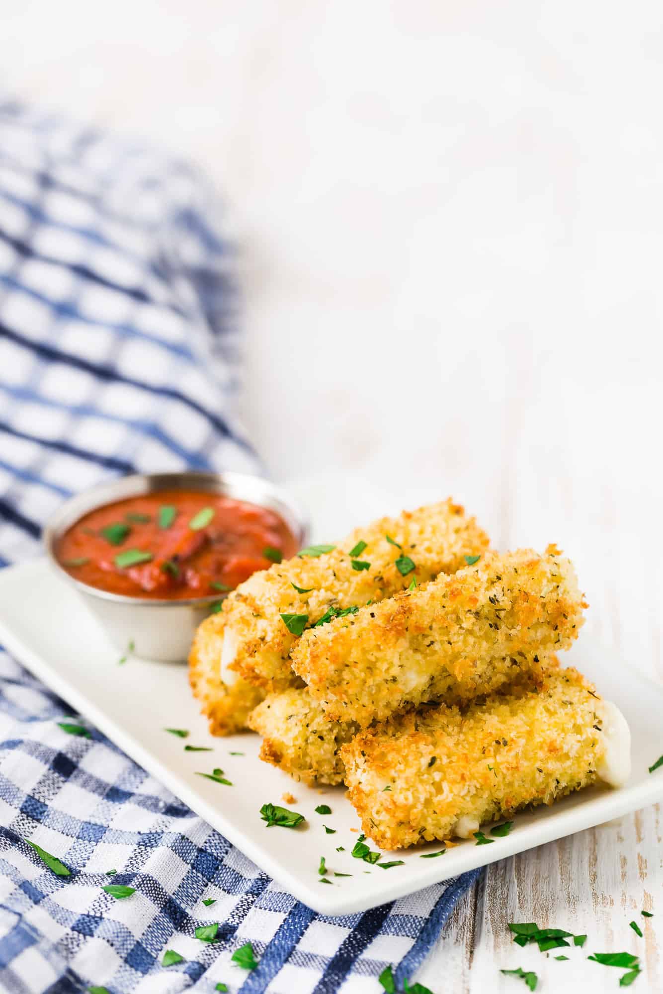 A plate of crispy mozzarella sticks sprinkled with parsley.