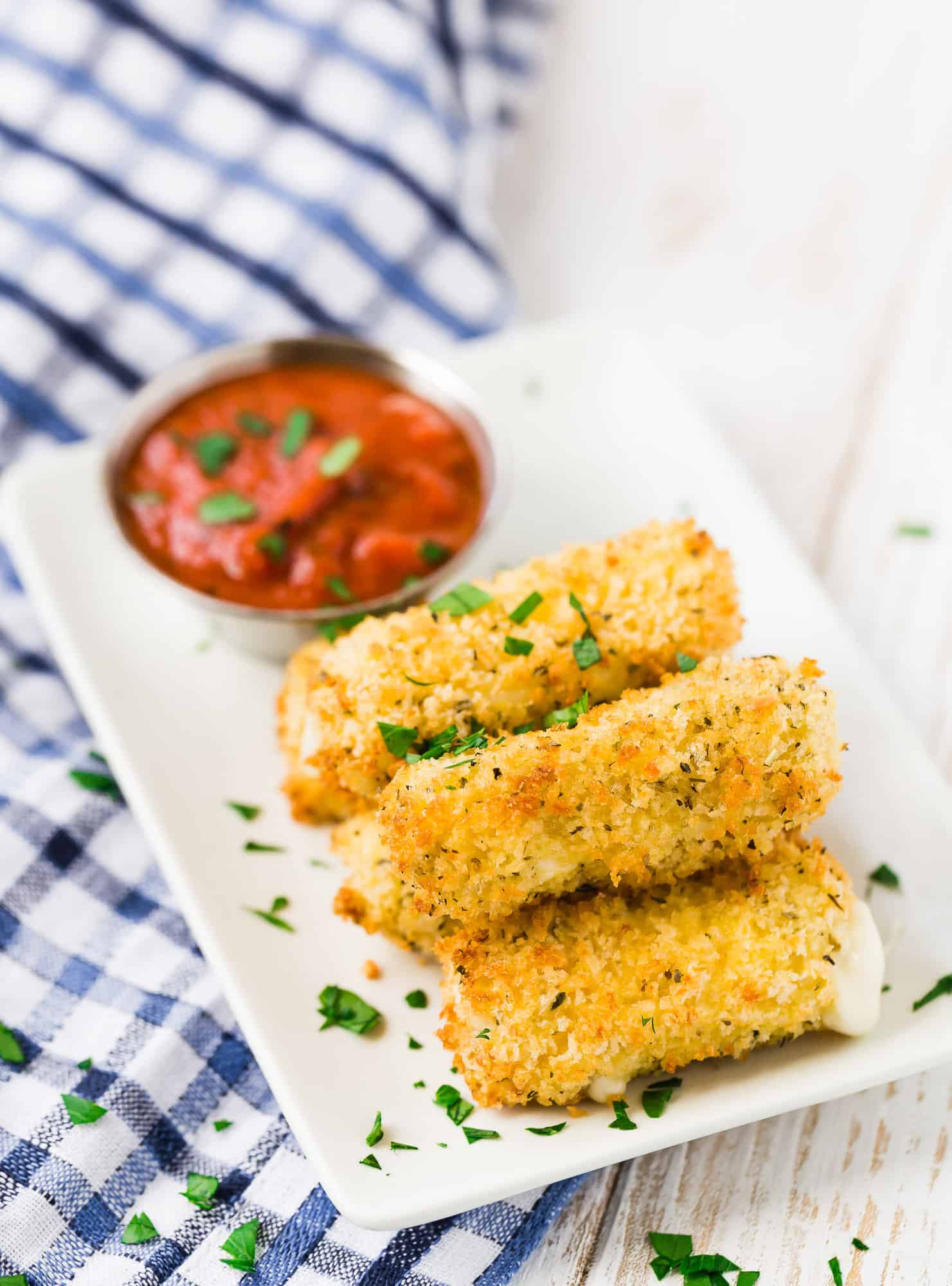 Stack of air fryer mozzarella sticks on a plate with marinara.