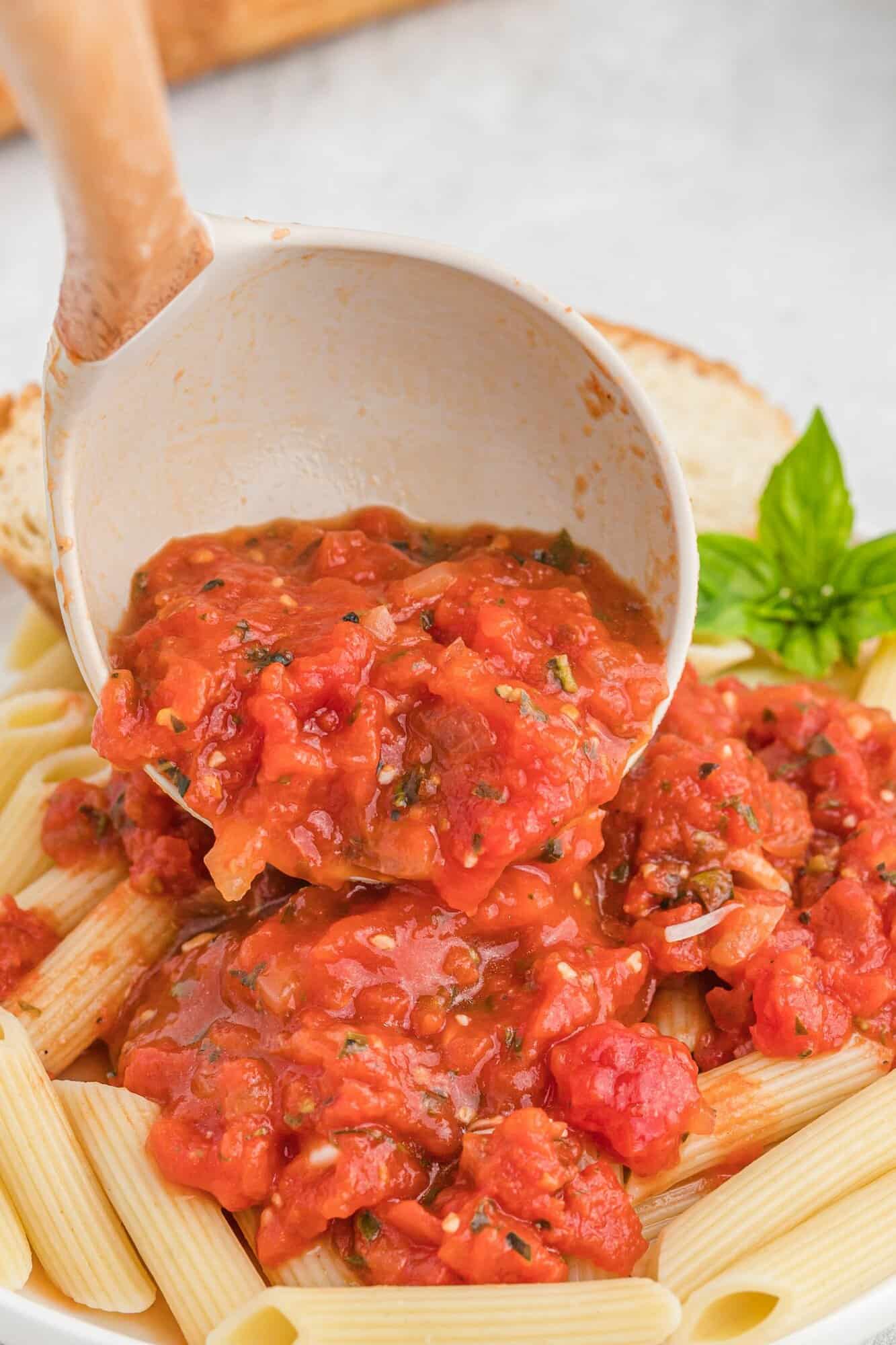 Pasta sauce being added to penne pasta.