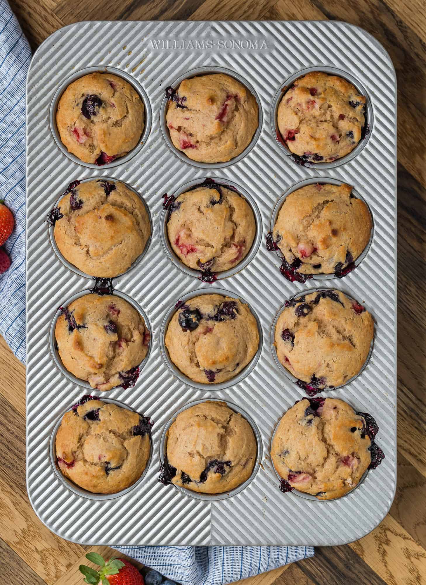 Muffin tin full of strawberry blueberry muffins.
