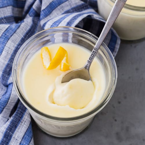 Lemon pudding in a small jar with a spoon and a lemon twist.