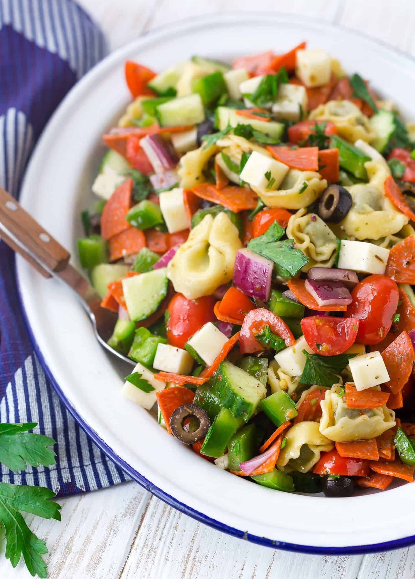 Pasta salad with olives, tortellini, cucumbers, pepperoni, and more.
