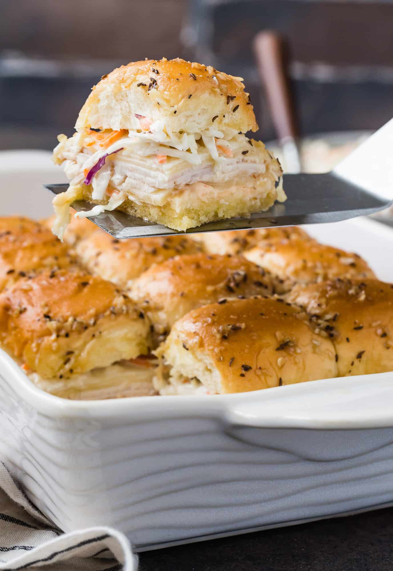 Turkey slider being lifted out of the pan on a large spatula.