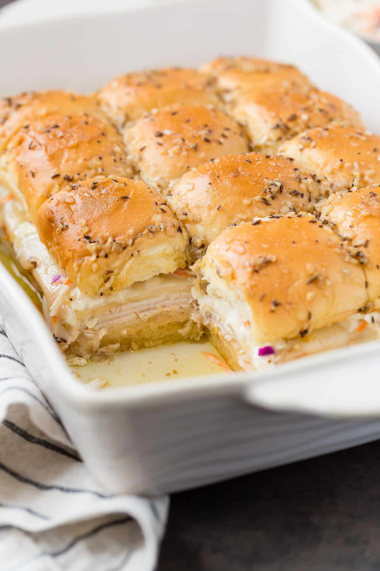 Turkey sliders in a baking dish with one removed.