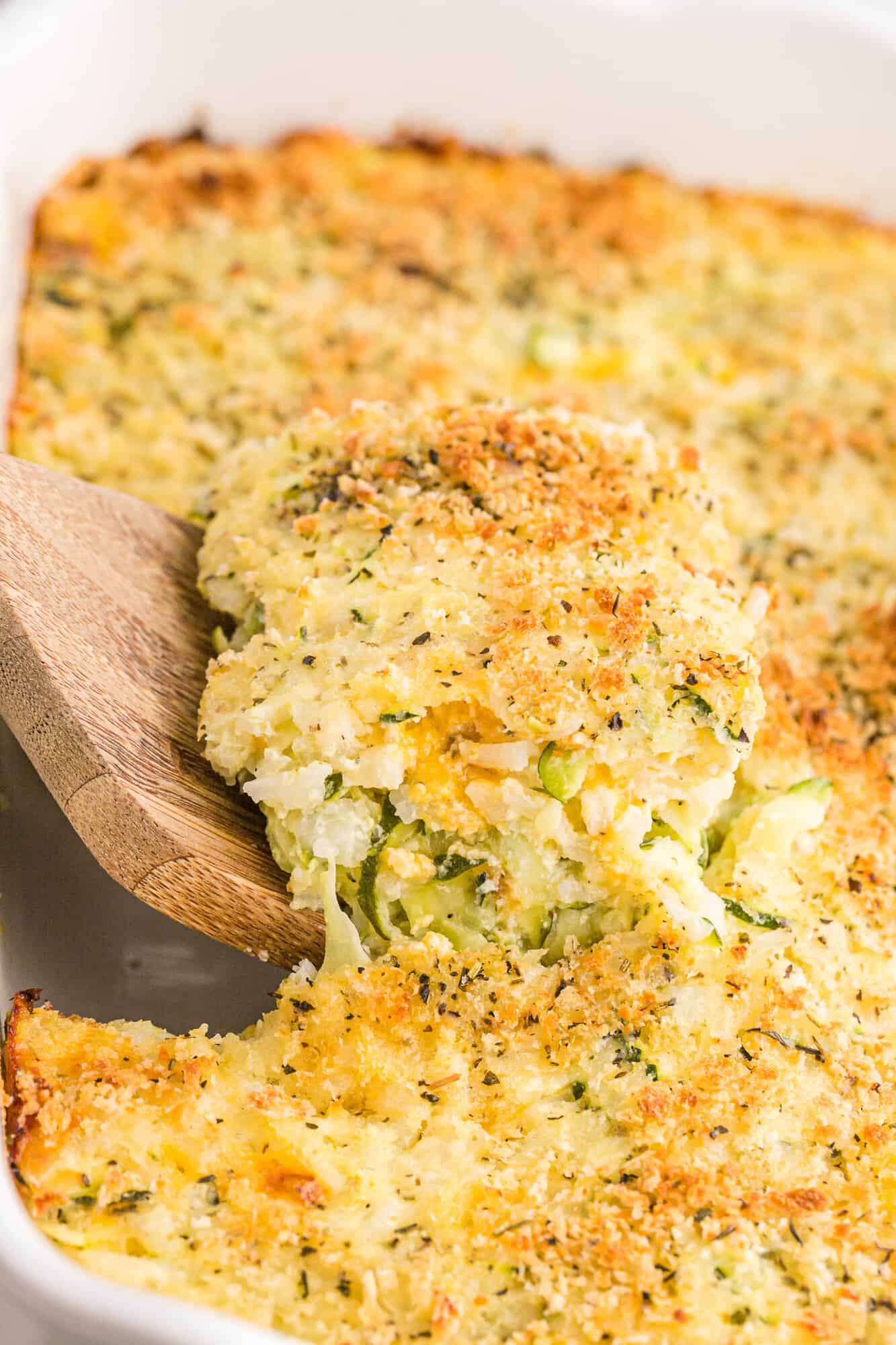 Casserole being scooped out of baking dish.