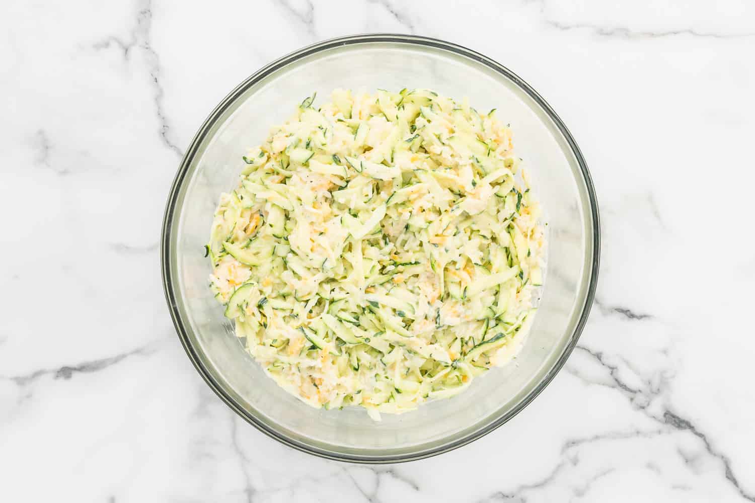 Zucchini mixture all combined in a glass mixing bowl.