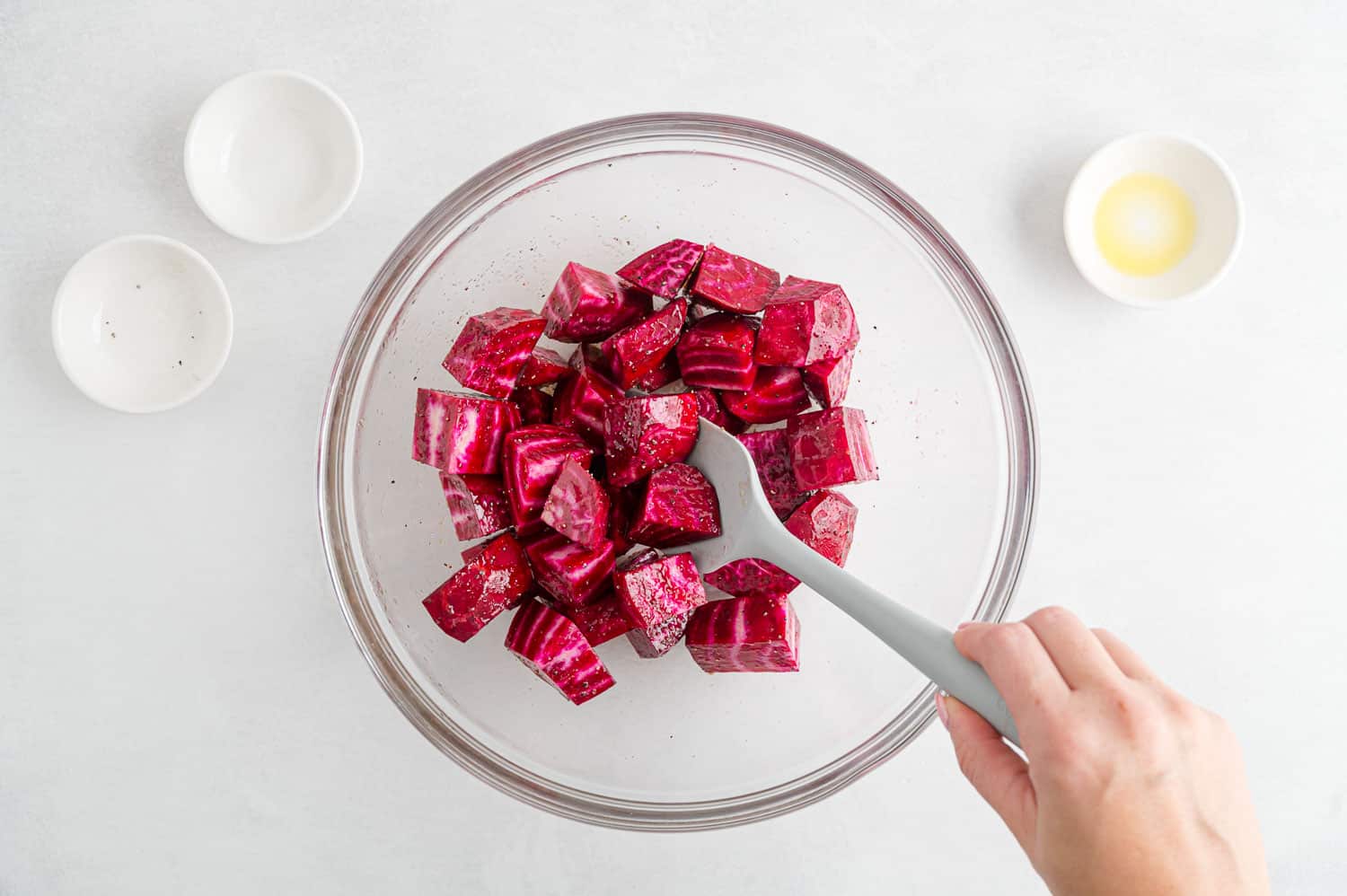 Beets being mixed with oil and seasonings.