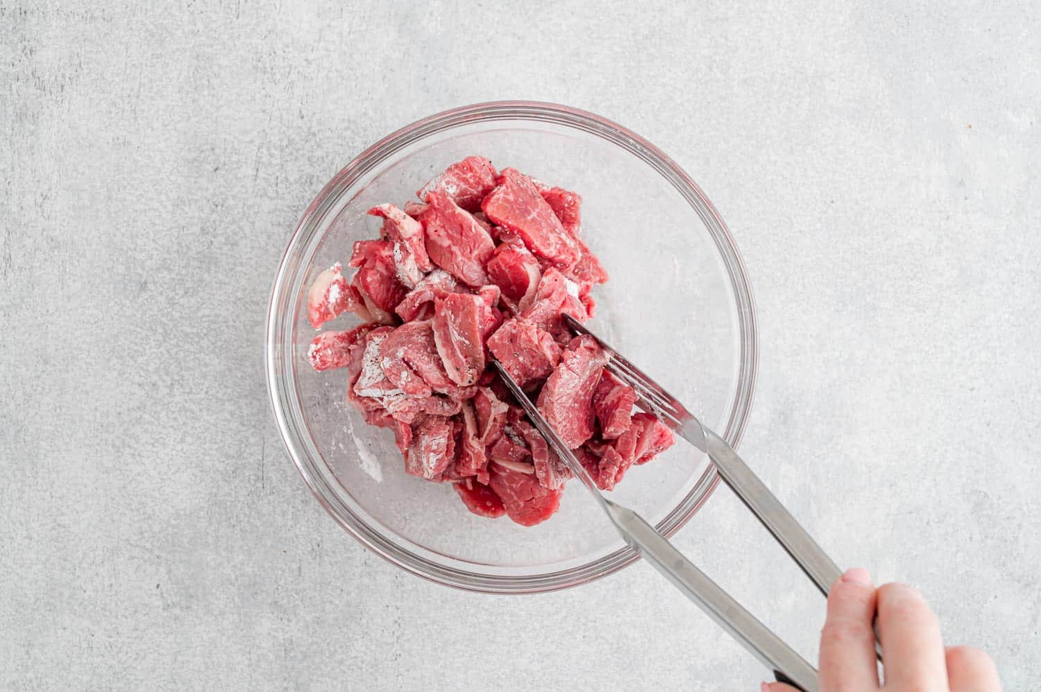 Beef slices being tossed with cornstarch mixture.