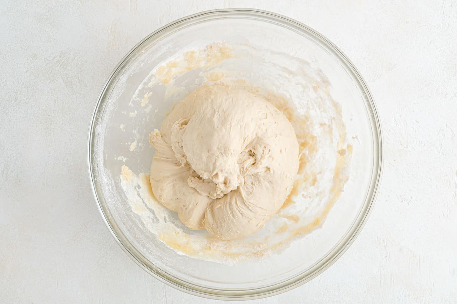 Uncooked homemade pizza dough in glass bowl.