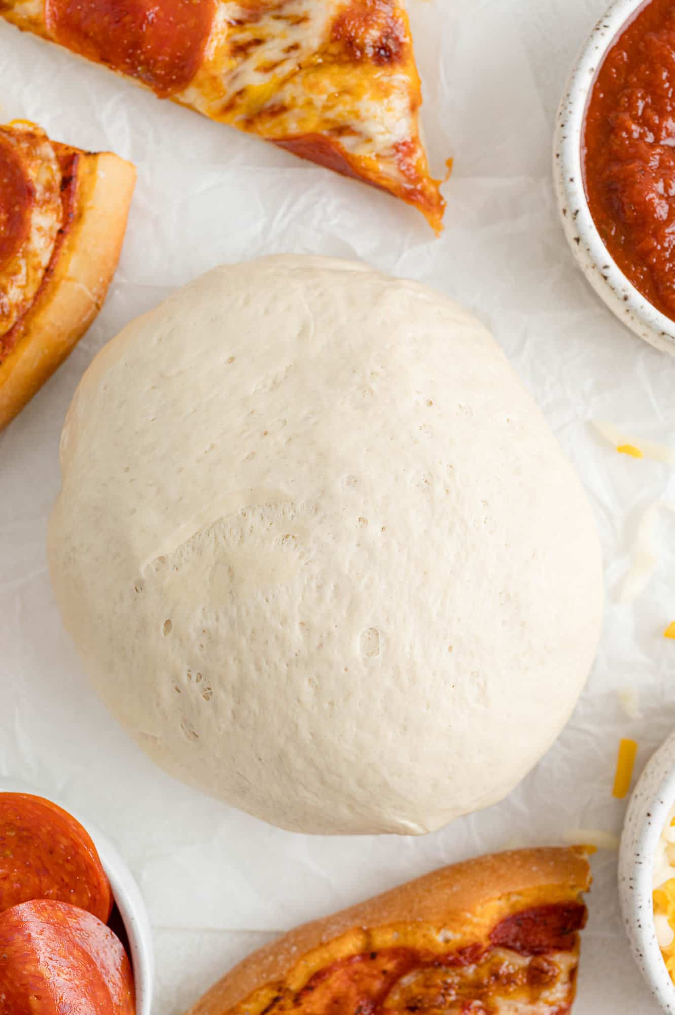 Pizza dough, surrounded by pizza slices.