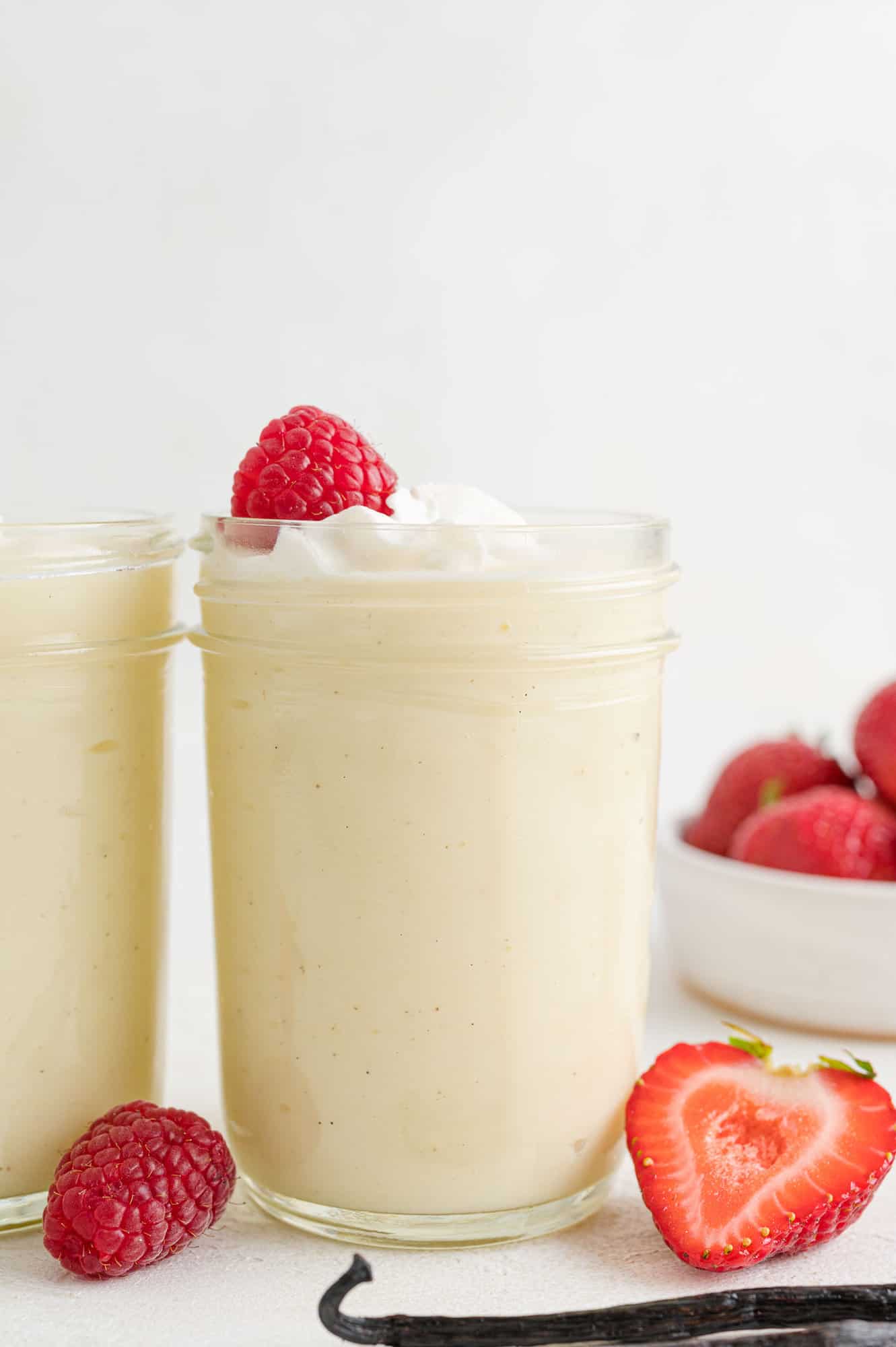 Vanilla pudding in a jar with whipped cream and a strawberry.