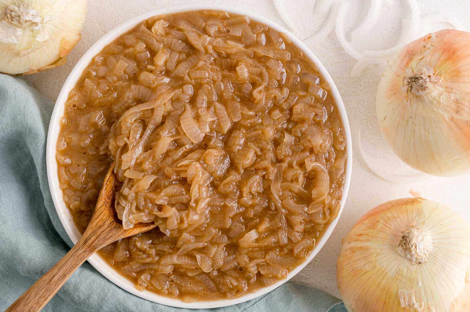 Caramelized onions in a bowl with wooden spoon.