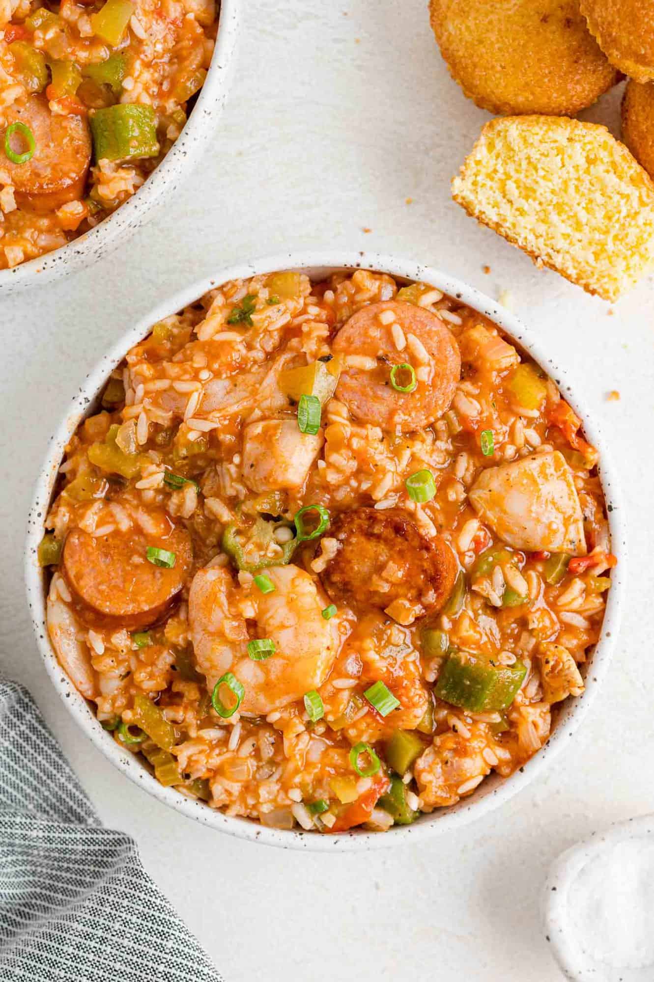 Jambalaya in serving bowl with corn muffins.