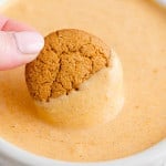 Gingersnap being dipped into creamy pumpkin dip.