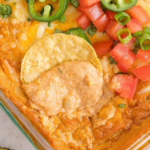 Refried bean dip with a chip being dipped in it.