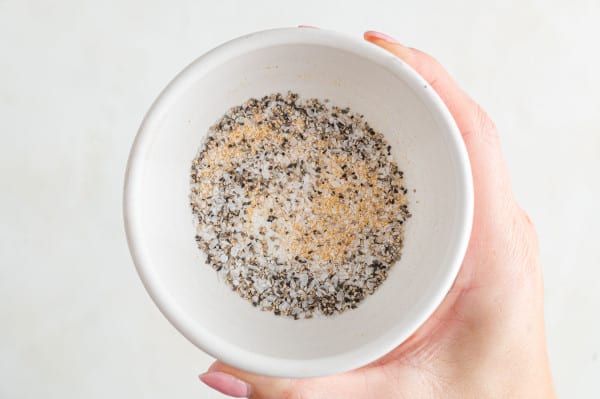 Overhead view of a hand holding a small bowl of seasoning.