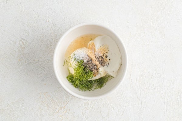 Ingredients for lemon dill sauce combined in a white bowl.