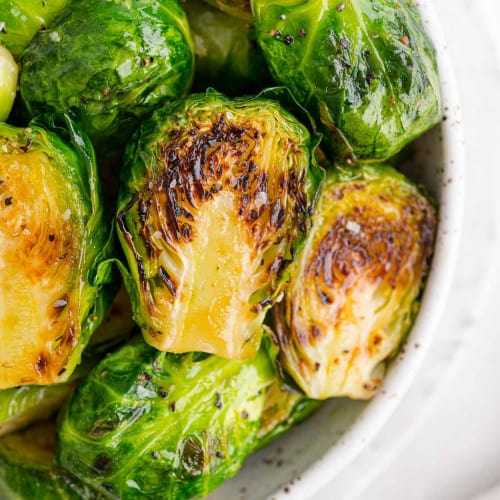 Perfectly sautéed Brussels sprouts in a white bowl.