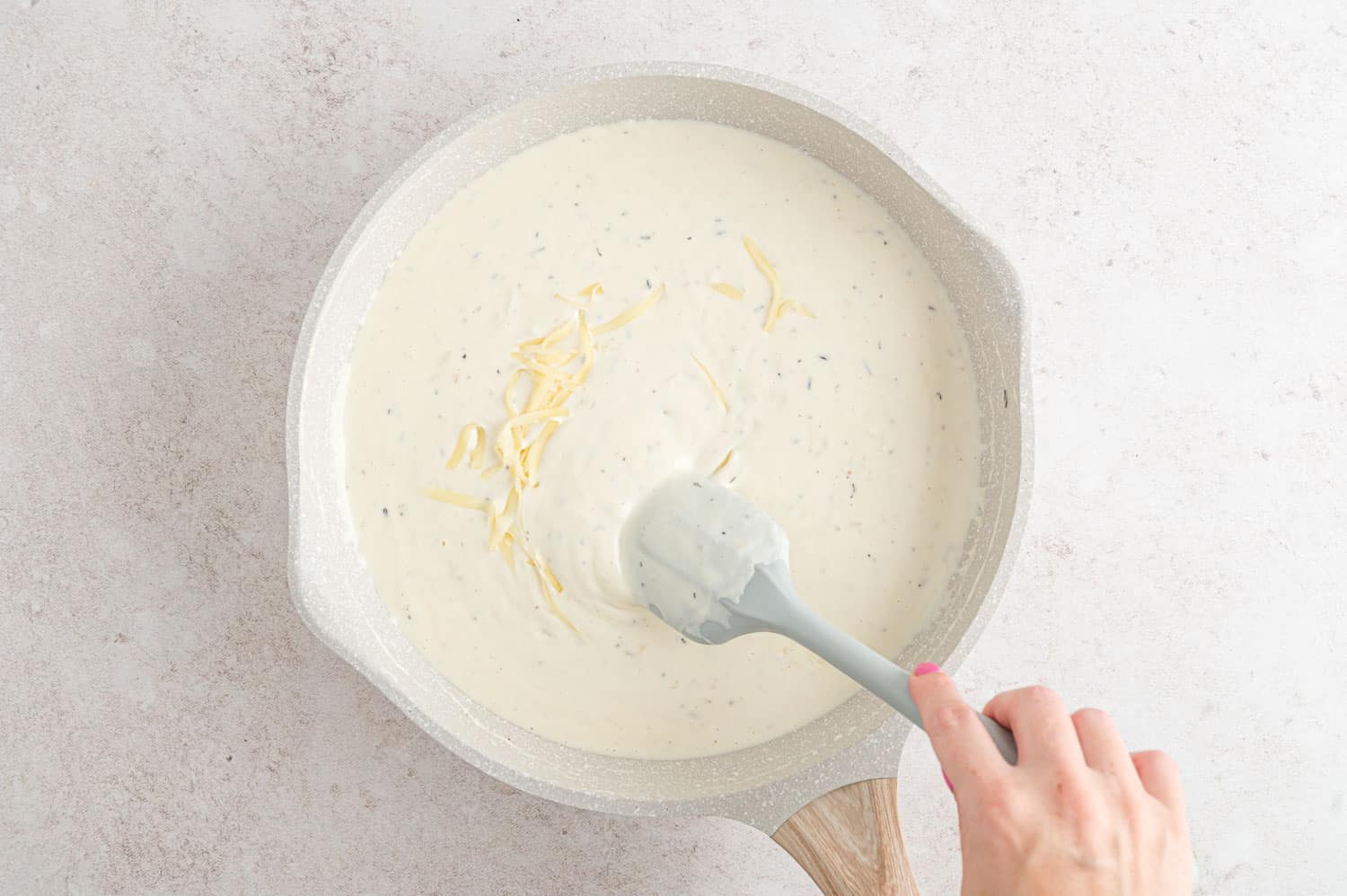 Cheese being stirred into white sauce.