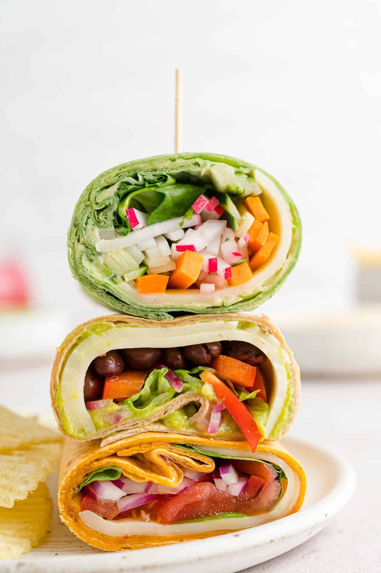 Three wraps, cut in half and stacked on a plate.