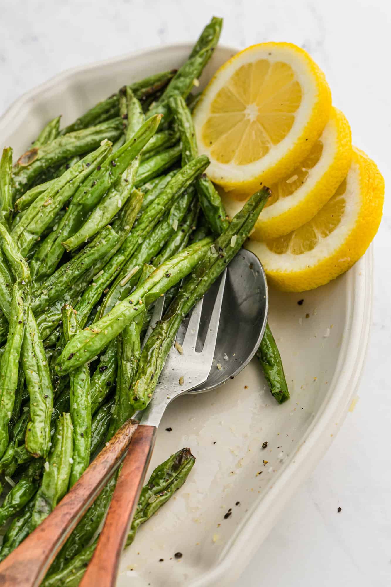 Green beans on a platter with lemon slices.