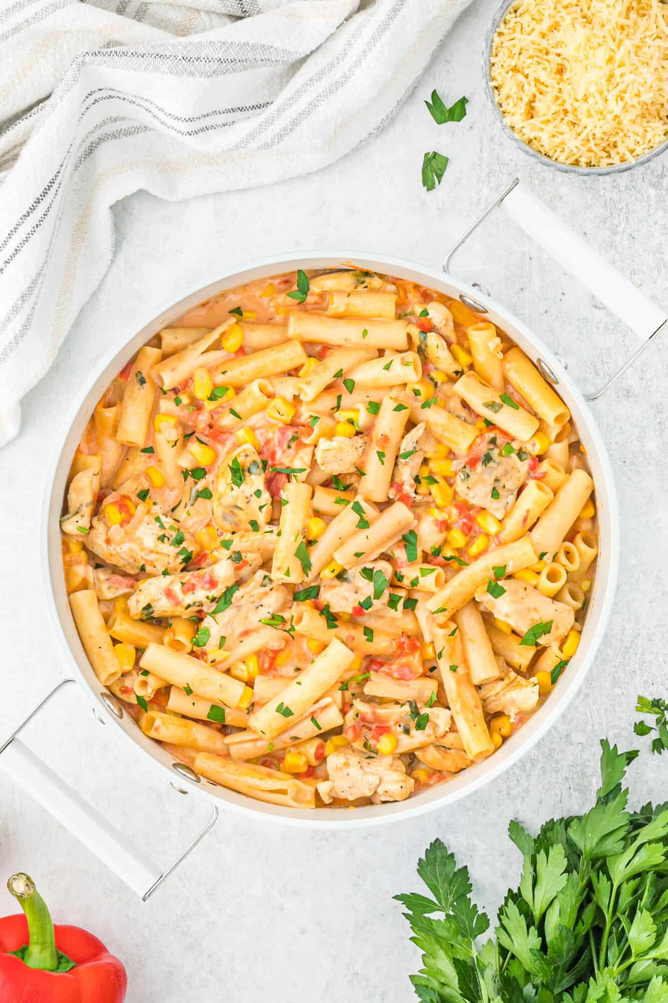 Overhead view of a bowl of Cajun chicken pasta surrounded by various ingredients.