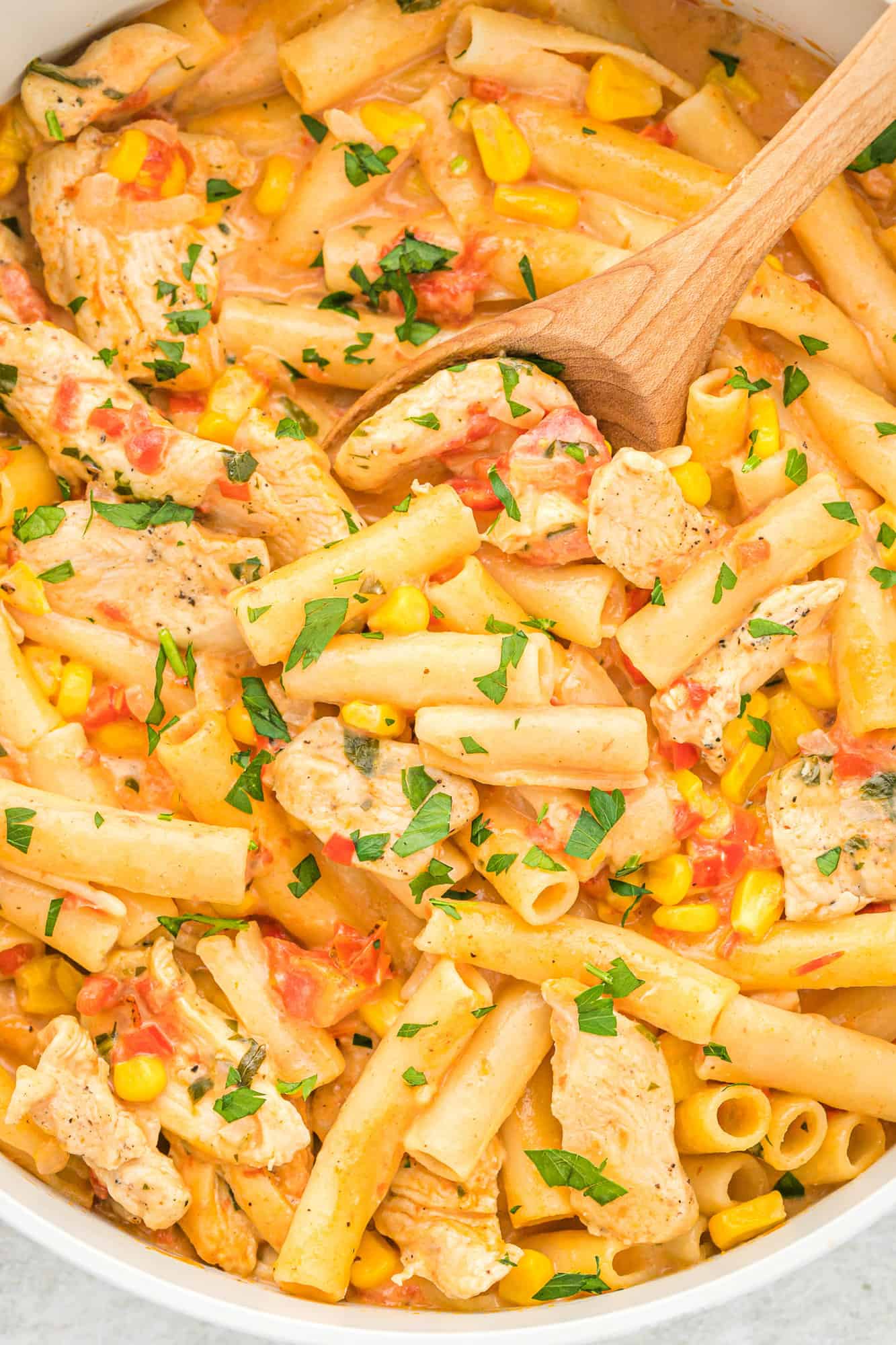 Cajun chicken pasta in a pan with a wooden spoon.