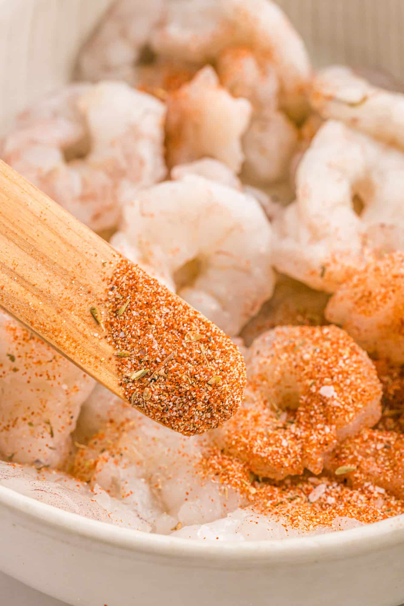 Cajun seasoning being added to shrimp.